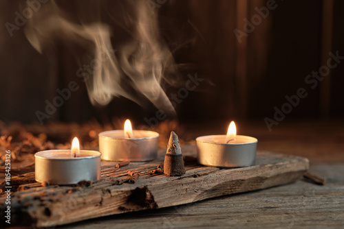 Three Candles and Incense Burning on Wooden Surface in a Dim Space