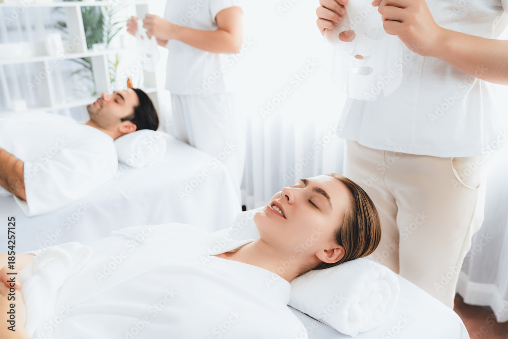 Obraz premium Serene modern daylight ambiance of spa salon, couple customer indulges in rejuvenating with facial skincare mask. Facial skin treatment and beauty cosmetology procedure for face. Quiescent
