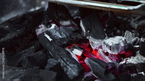 A close-up of wind-blown charcoal glowing red on a barbecue grill