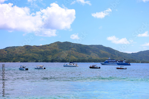 Boats Anchored in Clear Tropical Waters with Mountainous Island