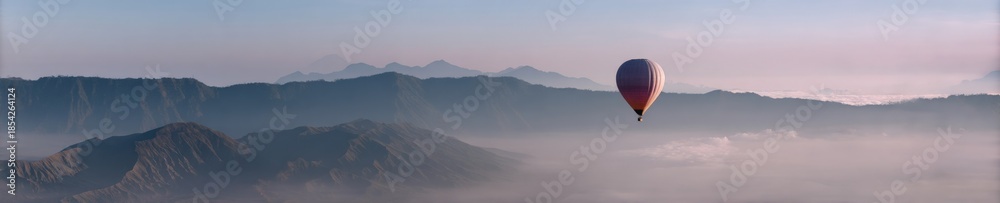 Fototapeta premium Enchanting hot air balloon over misty mountain range at sunrise
