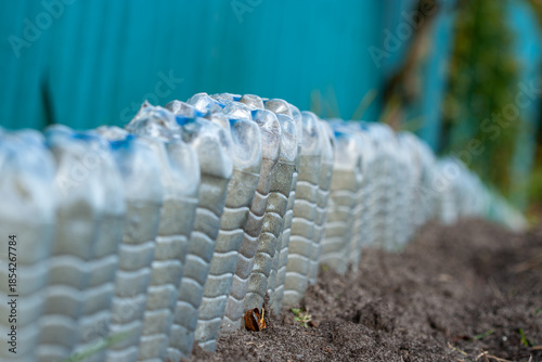 фотографія A creative DIY garden border made by burying clear plastic water bottles upside down in soil