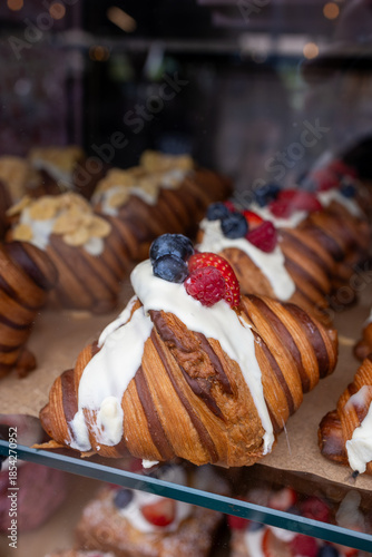 Artisan croissants with cream and fresh berries in bakery display
