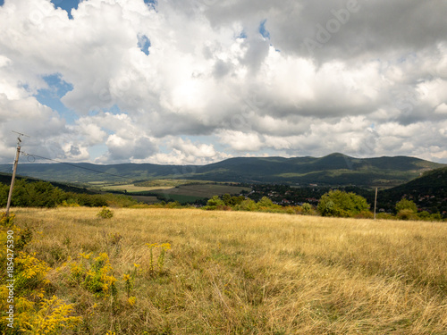 Obraz na plátne grassy field with view of buda hills and village