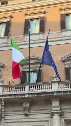 Low-angle view flags of Italy and European union flying on balcony of public building in Rome Concept for financial treated, unique currency and financial bond. Shooting in slow motion.