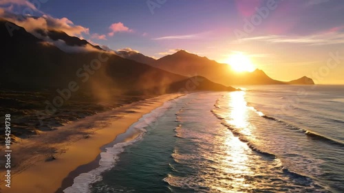 Stunning aerial view of a beautiful beach at sunset with mountains and ocean.