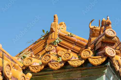 Quadro su tela Detail of a Ming Dynasty yellow roof corner with mythical beast figures and weeds growing in cracks
