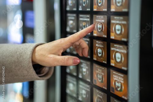 Fotografie Hand choosing cappuccino coffee from automatic vending machine