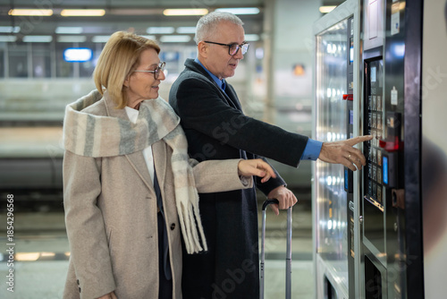 Bilde på lerret Senior couple buying snack from vending machine at station