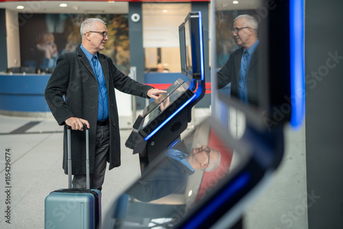 Photos Senior man using self-service check-in kiosk at airport