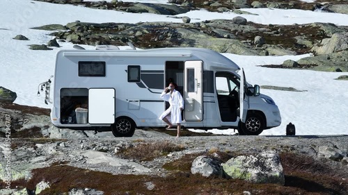 Enjoying Morning Coffee Outside a Camper in Snowy Landscape