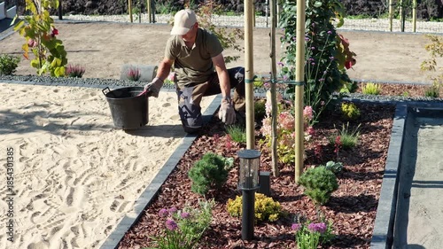 Caucasian Gardener Works on Plants in a New Garden Area During Sunny Weather