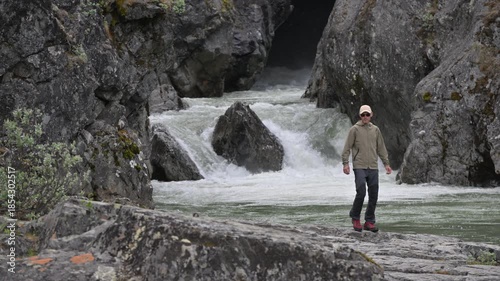 Man Walks Near Rushing Water in Rocky Landscape During Daytime