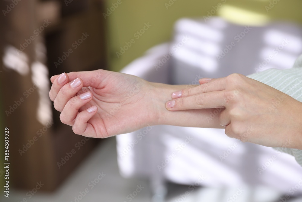 Fototapeta premium Woman checking her pulse with fingers at home, closeup