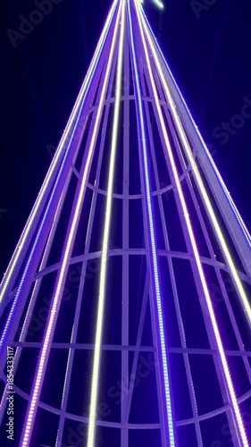 A neon-lit metal Christmas tree structure at night