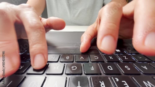 Front view of fingers typing on a laptop keyboard, focusing on black keys, symbolizing technology, digital work, communication, productivity, and the modern lifestyle of online activity