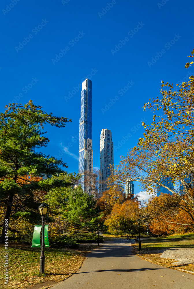 Obraz premium Central Park autumn path with Manhattan skyscrapers and blue sky above NYC
