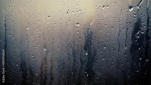 Close-up view of water droplets on a glass surface, creating a textured and reflective pattern with a blurred background.