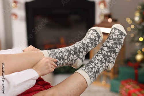 Quadro em tela Woman putting on cozy socks at home, closeup. Space for text