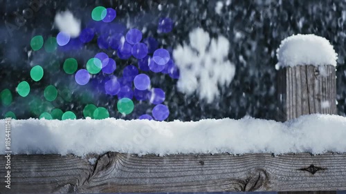 winter scene with snowflakes and blurred lights behind a wooden fence