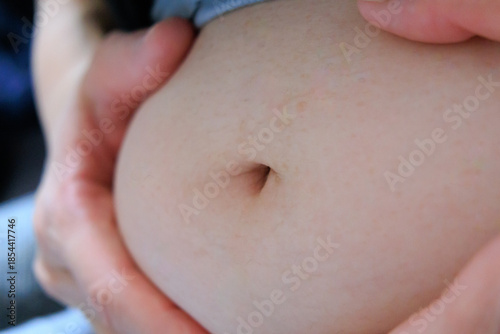 太った女性のおなかを手で抑える　腹　肉　脂肪　体型