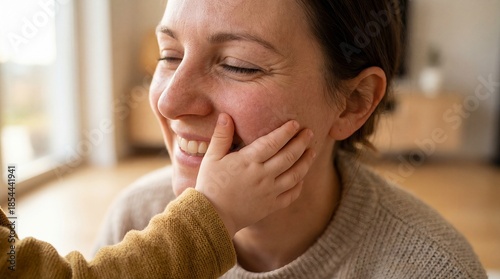 Close-up of child hand gently touching smiling mother's cheek symbolizing affection and family bond.