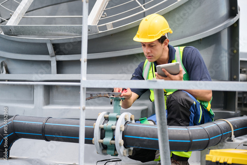 An engineer inspecting pipes with a tablet in an industrial setting