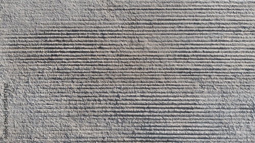 Brushed concrete surface texture, fine parallel broom marks across grey cement, sidewalk or pavement finish, tactile industrial background, uniform daylight 