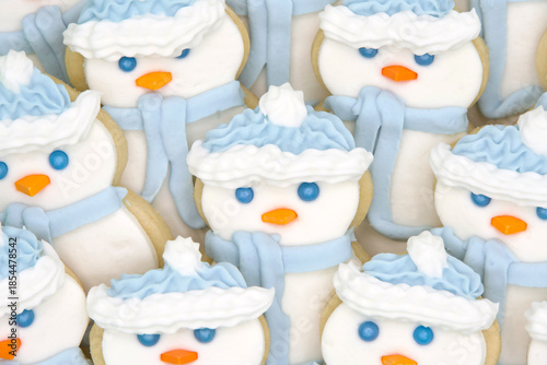 Close up on snowmen sugar cookies decorated with mashmallow fondant, candy eyes and nose, royal icing hat and scarf. Festive holiday treats.