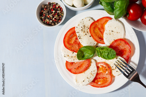 A plate of delicious salad with fresh mozzarella and juicy tomatoes, top view