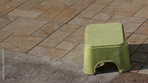 Bright Green Step Stool on Stone Floor in a Sunlit Outdoor Setting