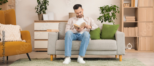 Handsome man reading book o...