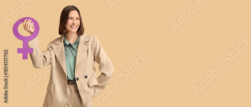 Tableau sur toile Beautiful young woman holding female symbol and showing muscles on beige background
