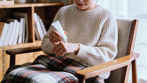乾燥した冬の室内でハンドクリームを塗る女性