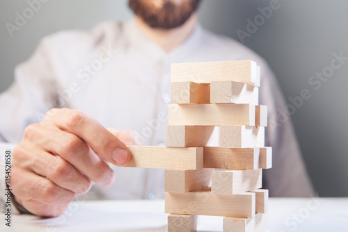 businessman putting wooden blocks on wooden blocks as concept of strategy and business success.