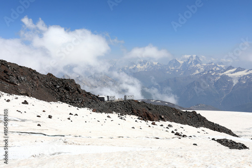 Mountain refuge on mount Elbrus with snowy rocks and dramatic sky