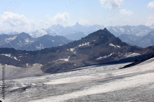 Snow-capped alpine mountain range with glaciers and rugged peaks under partly cloudy skies