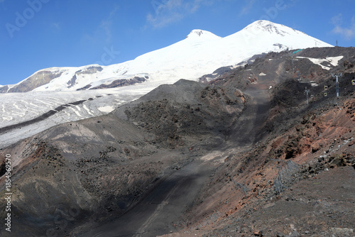 Snow-capped Mount Elbrus with dark, rocky slopes and glacier below