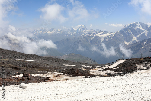 Snowy mountain landscape with rocky terrain and peaks in clouds