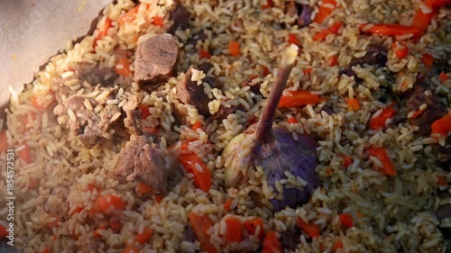 Freshly cooked hot pilaf in a metal cauldron outdoors in winter. A delicious Kazakh ethnic dish. Close-up.