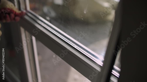 Worker adjusting aluminum window frame with rubber mallet