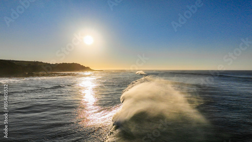 Quadro em tela The sun is setting over the ocean, casting a warm glow on the water