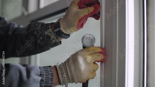 Worker installing glazing bead while fixing glass in window frame