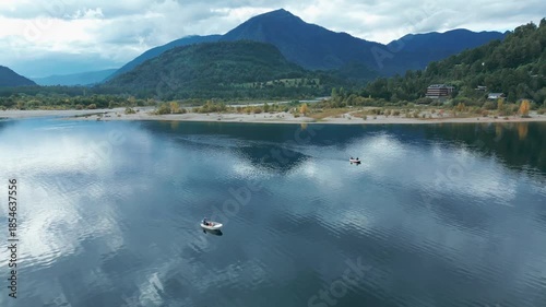 Wallpaper Mural Panning drone aerial of boats sailing on calm lake with reflections, mountains backdrop, beach shoreline, and autumn foliage Torontodigital.ca