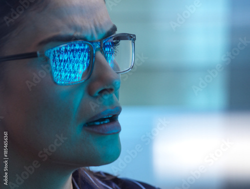 Woman looking seriously at screen reflecting binary code during cyber attack