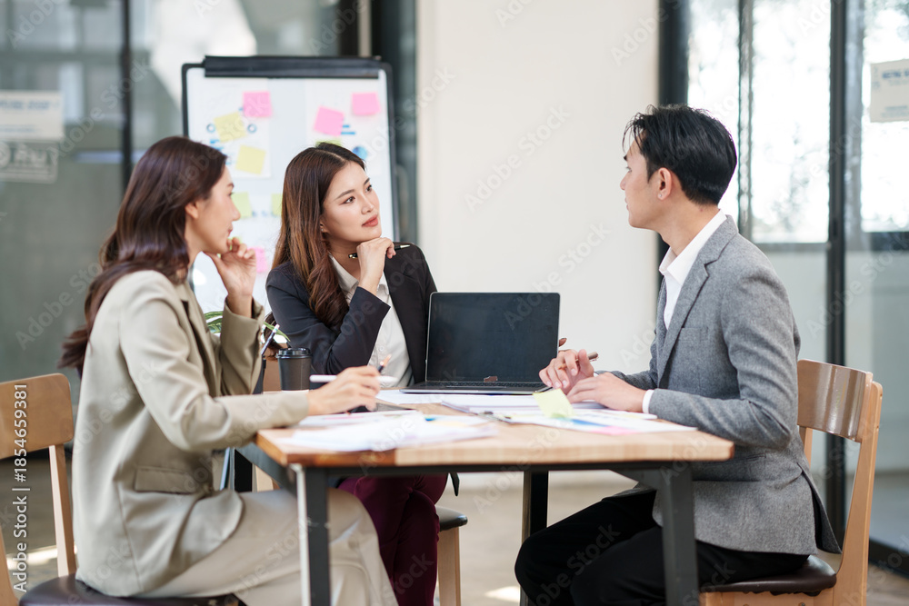 Fototapeta premium Group of Asian businesspeople sits down for a business investment planning meeting.