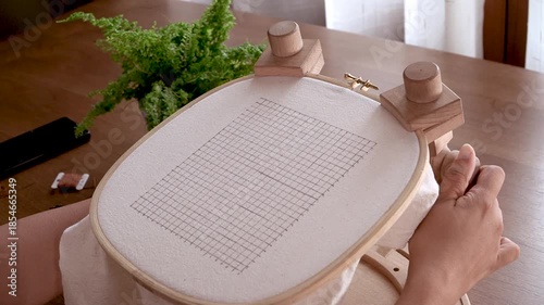 Securing the Frame: Hands Tightening the Screw on an Embroidery Hoop Stand.