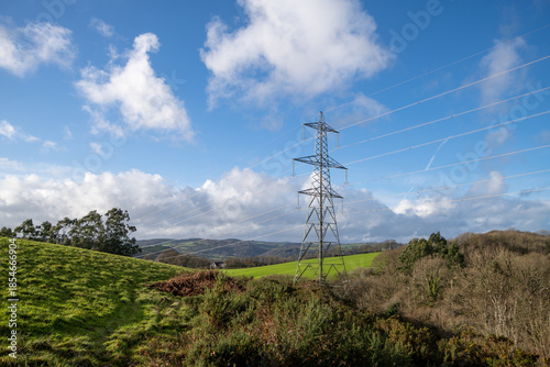 Devonshire countryside with rolling green fields and blue skies. Electricity pylons cross the landscape. Hiking and country walks. English rural landscape.
