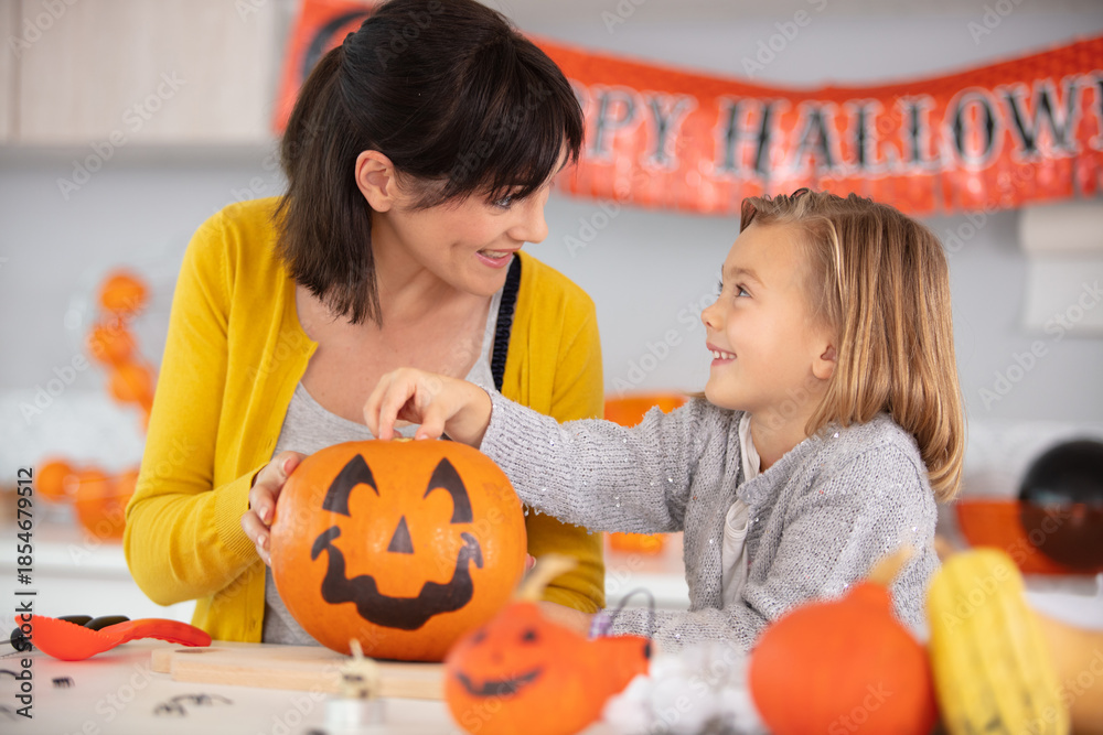 Fototapeta premium a mother and her daughter carving pumpkins for halloween
