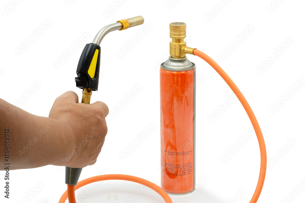 Naklejka premium Close-up of a hand holding a gas torch connected to a fuel canister, representing industrial heating, soldering, craftsmanship, safety awareness, and professional tool usage.